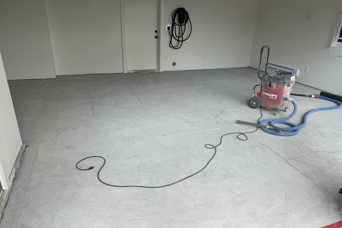 Bare concrete garage slab with grinding equipment on site before epoxy coating