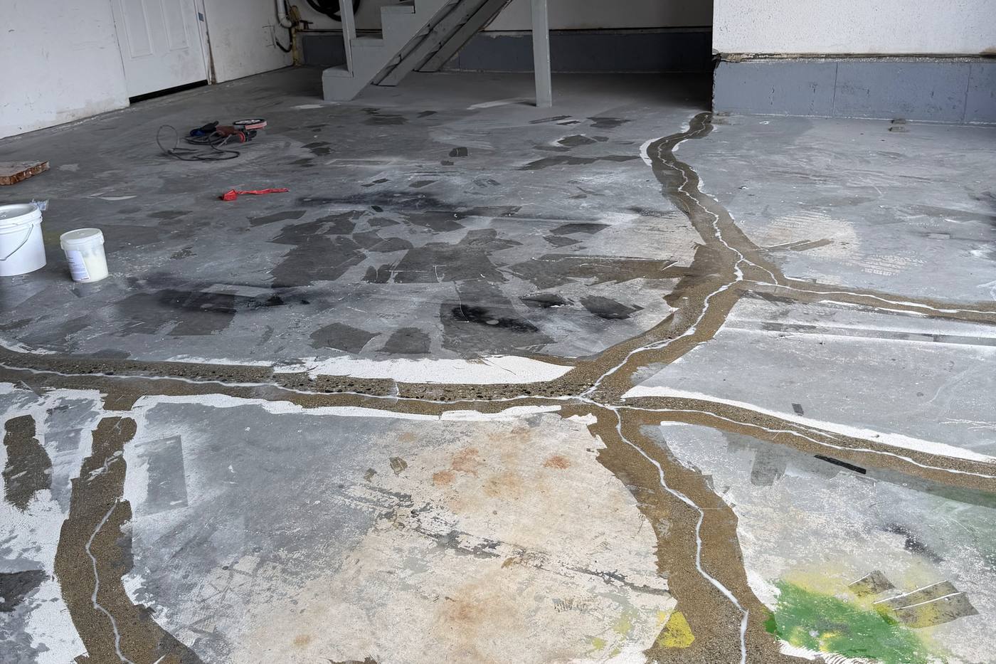 Ground concrete garage slab with cracks routed and filled before epoxy coating