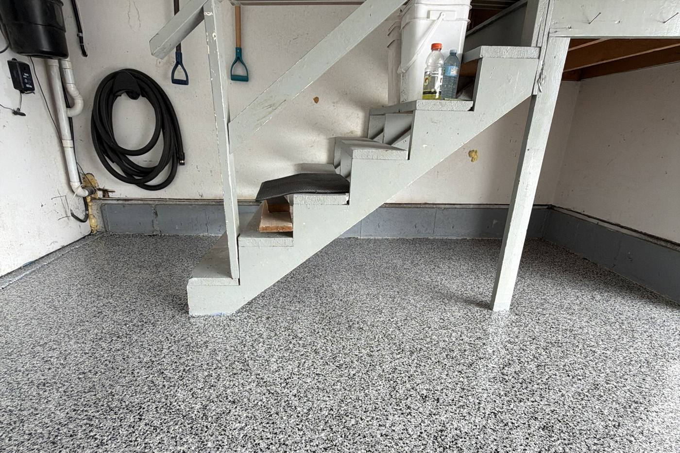 Finished epoxy garage floor with clear topcoat around interior stairs in Coquitlam